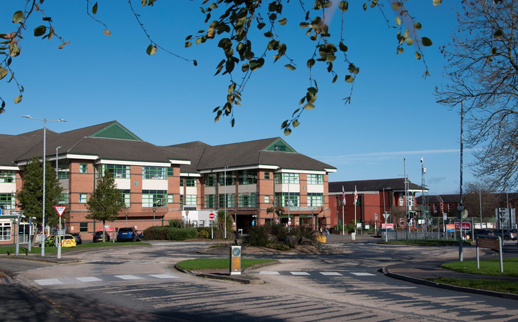 A photo showing the exterior of Bolton Royal Hospital, a red-brick building, under a blue sky