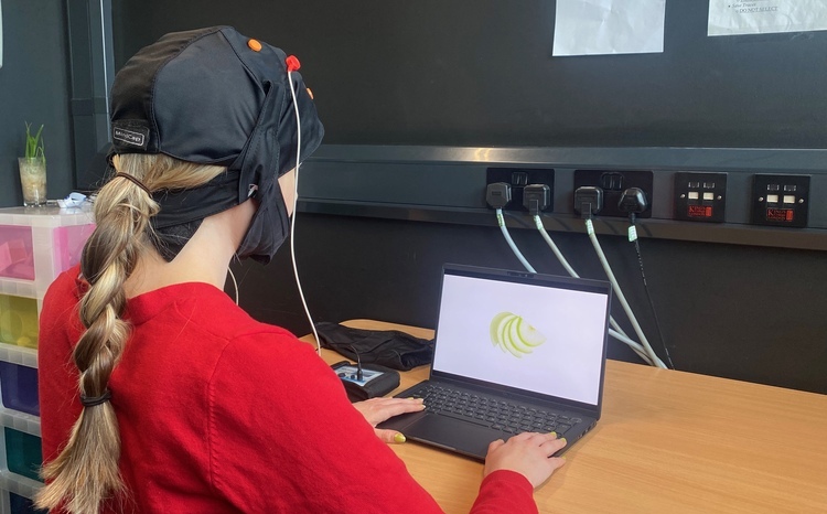 A woman wearing a Neurotherapeutics device sitting at a laptop